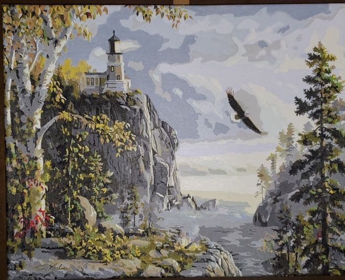 Guiding Light paint by numbers completed by a 2021 prize winner: a clifftop lighthouse with an eagle over the water