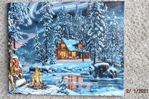 Aurora Bliss paint by numbers completed by Dennis: a lit cabin in snowy pines beside a campfire under the northern lights