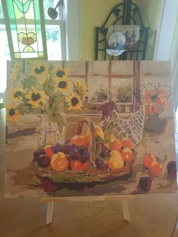 Paint by numbers completed by a customer: sunflowers and a basket of fruit on an easel