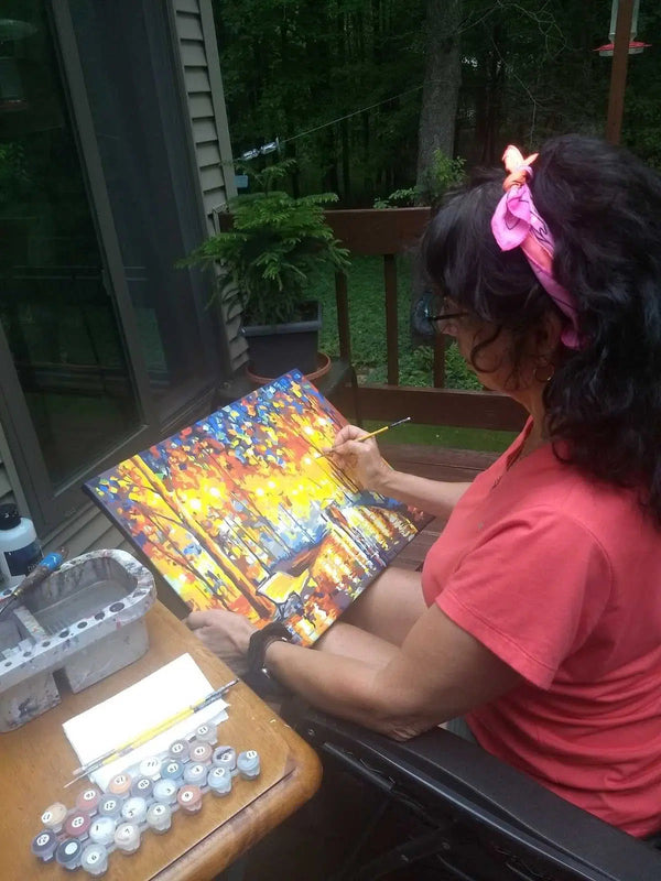 Paint by numbers completed by Pam C: a painter filling in a brightly colored canvas at a table