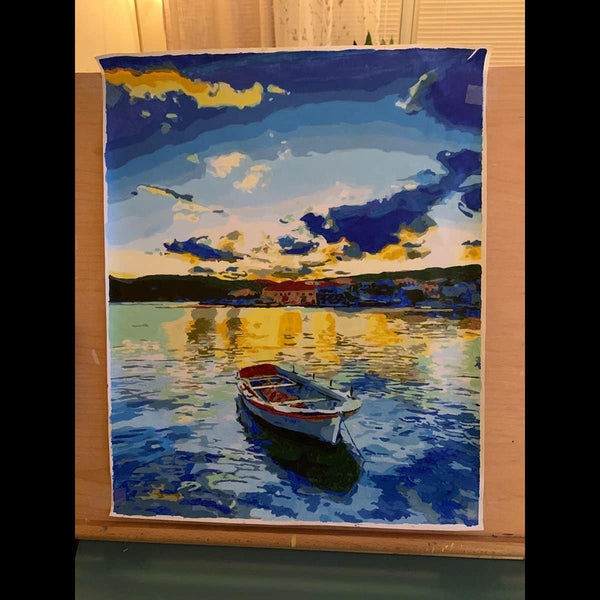 Paint by numbers completed by a customer: a canoe drawn up on a lake at sunset, on an easel